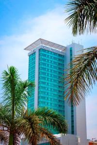 a tall blue building with palm trees in front of it at Hotel Presidente Luanda in Luanda