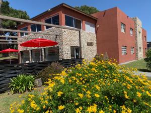 un edificio con un paraguas rojo y algunas flores amarillas en Dunas Sur, en Villa Gesell