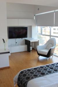 Habitación blanca con silla y TV en Edificio Monir en Bogotá