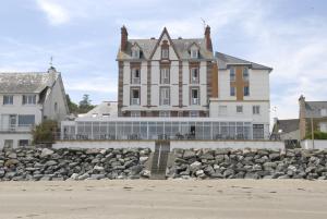 Hôtel Miléade de la Plage - Binic في بينيك: مبنى كبير على الشاطئ مع كومة من الصخور