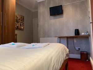 1 dormitorio con 2 camas y TV en la pared en Twickenham Guest House, en Twickenham