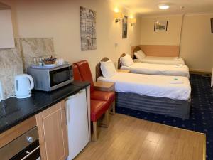 a hotel room with two beds and a tv at Twickenham Guest House in Twickenham