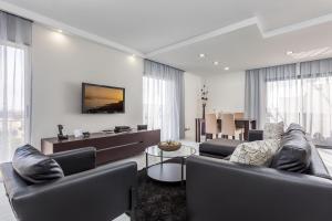 een woonkamer met twee banken en een televisie aan de muur bij D_Loft in Albufeira