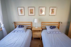 2 camas individuales en una habitación con escritorio y cuadros en la pared en Le Gîte du Moulin, en Ribeauvillé