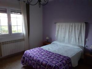 1 dormitorio con 1 cama con edredón morado y 2 ventanas en Apartamento El Portiel, en Gotor
