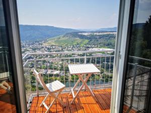a table and two chairs on a balcony with a view at Moselsteig Lodge in Starkenburg