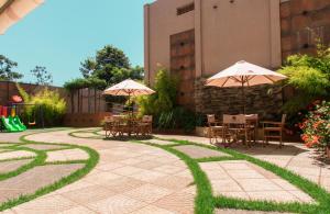 un patio con tavoli, sedie e ombrelloni di Nova Hotel a Ciudad del Este