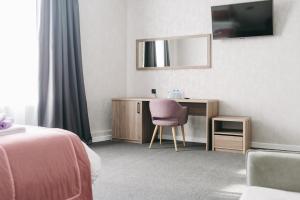 ein Hotelzimmer mit einem Schreibtisch und einem rosa Stuhl in der Unterkunft Гостиница ИВАНОВООТЕЛЬ in Iwanowo