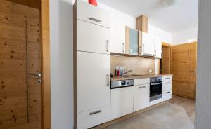 eine Küche mit weißen Geräten und Holzwänden in der Unterkunft Ferienwohnung Alpenherz in Neustift im Stubaital