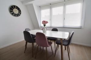 uma sala de jantar com mesa e cadeiras e um relógio em Rent a flat - Montgomery em Bruxelas