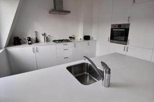 uma cozinha com um lavatório e uma bancada branca em Rent a flat - Montgomery em Bruxelas