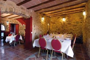 una sala da pranzo con tavoli bianchi e sedie rosse di Hotel Rural Barranc De L'ínfern a Vall de Ebo