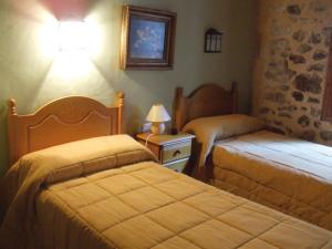 Hotel Rural Barranc De L'ínfern في Vall de Ebo: غرفة نوم بسريرين ومصباح على طاولة