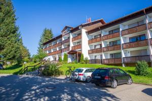 deux voitures garées sur un parking devant un immeuble dans l'établissement Ferienwohnung Nicole, à Missen-Wilhams