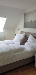 ein weißes Bett mit weißer Bettwäsche und Kissen in der Unterkunft Apartment Stockerau in Stockerau