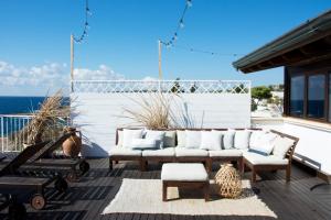 a patio with white furniture and the ocean in the background at Hotel Corallo in Santa Maria al Bagno
