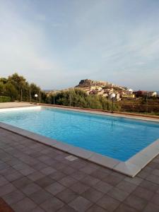 ein großer blauer Pool mit einem Hügel im Hintergrund in der Unterkunft happy sun apartment in Castelsardo