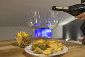 a person pouring wine into two wine glasses and a plate of food at Panoramic Penthouse - In the heart of Domodossola in Domodossola
