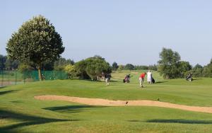 un grupo de personas jugando al golf en un campo de golf en Madame Vacances Les Maisons de Fontenelles, en LʼAiguillon-sur-Vie