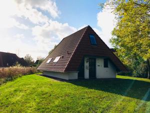 ein kleines Gebäude mit einem Dach auf einem Grasfeld in der Unterkunft Ferienhaus Anna in Dorum Neufeld