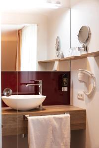 a bathroom with a sink, mirror, and towel rack at Hotel Restaurant Zum Hirschen in Donaueschingen