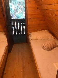two beds in a wooden room with a window at Dotik gozda in Železniki
