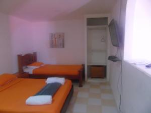 a small room with two beds and a television at Posada Miss Joyce House in San Andrés