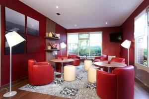 a restaurant with red chairs and tables in a room at Campanile Rouen Est - Franqueville Saint Pierre in Franqueville-Saint-Pierre