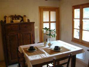 mesa de comedor con mantel blanco y 2 tazas en Le Camelie, en Brissago Valtravaglia