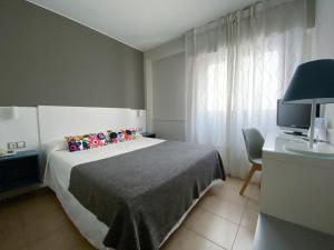 a bedroom with a bed, desk, and television at Hotel Rio Arga in Zaragoza