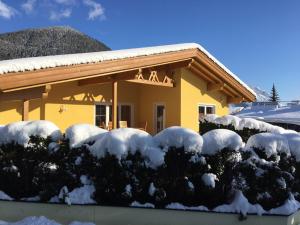 a house with snow covered bushes in front of it at Landhaus Grünberg in Obsteig