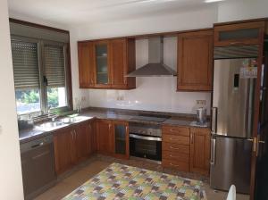 a kitchen with wooden cabinets and a stainless steel refrigerator at Playa America! in Nigrán