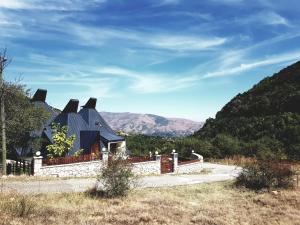 a house with a black roof with mountains in the background at Vila Piramida in Bitola