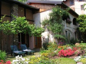 a house with two chairs and a bench in a garden at Le Camelie in Brissago Valtravaglia