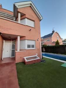 a brick house with a swimming pool in front of it at Chalet Avila Rooms in Madrid