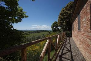 a wooden rail next to a building with a view of a field at Fattoria Armena in Buonconvento