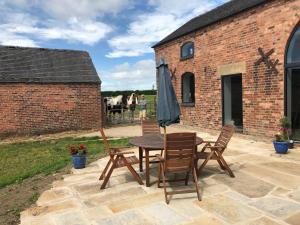 eine Terrasse mit Tisch und Stühlen und einem Sonnenschirm in der Unterkunft Lady lane stables in Denby