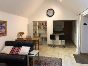 ein Wohnzimmer mit einer Couch und einer Uhr an der Wand in der Unterkunft Lady lane stables in Denby