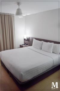 1 dormitorio con 1 cama grande con sábanas blancas en Hotel Mega, en Lima