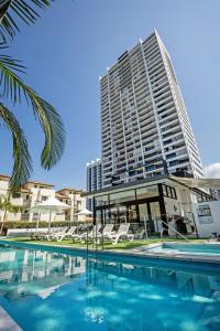 a swimming pool with a tall building in the background at Ultra Broadbeach in Gold Coast