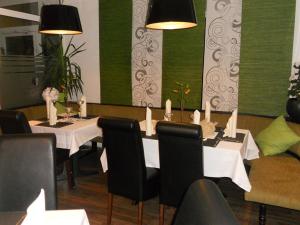 un comedor con una mesa con mesas blancas y sillas negras en Hotel und Restaurant Rosenkranz, en Markranstädt