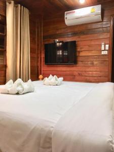 a bedroom with a white bed with a tv on the wall at Life and Love house in Ban Na Noi