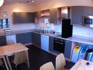 a kitchen with blue cabinets and a wooden table at Wayfarers Independent Hostel in Penrith