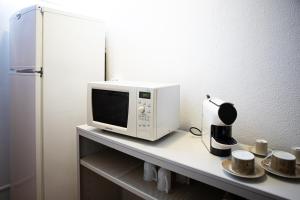 un forno a microonde seduto sopra un bancone con tazze di Silva's Guest House a Vila Nova de Gaia