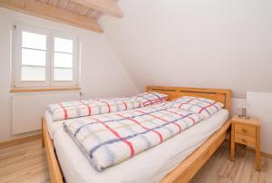 a bed with a wooden frame in a room with a window at Achterdeck - Hüs in Lee in Süddorf