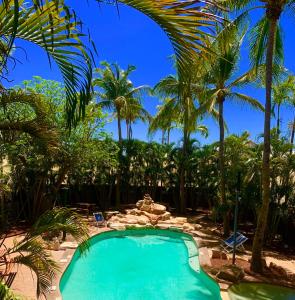 a swimming pool in a resort with palm trees at Roey Backpackers and Party Bar in Broome