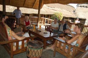 a group of people sitting in chairs under an umbrella at Ravine Lodge in Livingstone