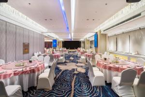 a banquet hall with tables and white chairs and a stage at Sun Moon Lake Hotel Dalian大连火车站店 in Dalian