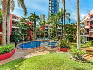 a swimming pool with palm trees and buildings at Enderley Gardens Resort in Gold Coast