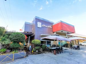 un restaurante con mesas y sombrillas frente a un edificio en Reddoorz Plus near Robinsons Place Gensan en General Santos